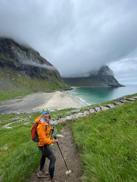 A hiker on the green trail above Kvalvika beach in summer.
