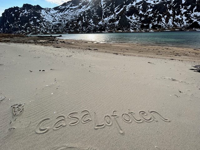 The beach at Casa Lofoten, with 'casa lofoten' written in the sand.