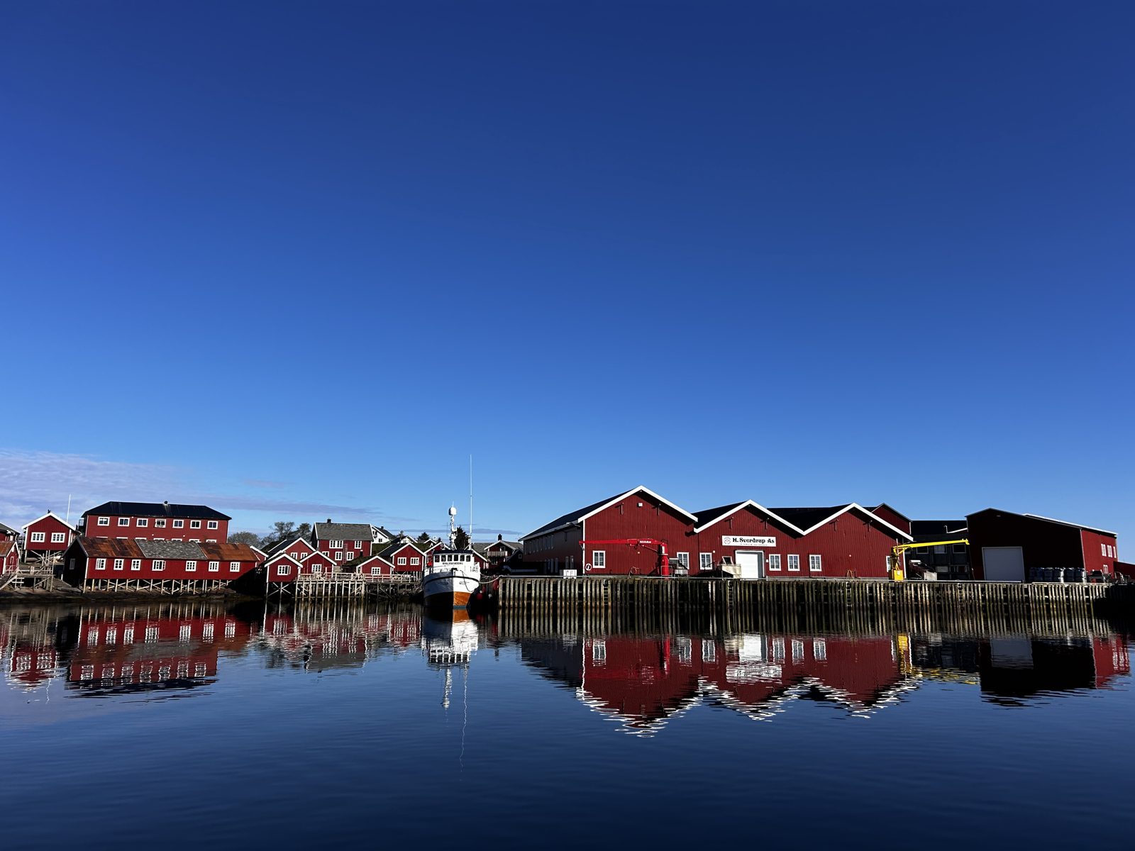 Red sea houses at Reine and Sakris&oslash;y reflected in the harbour