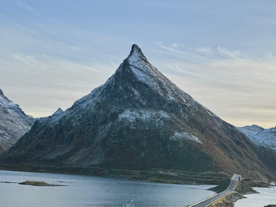 Volandstind rising as a sharp pyramid above the fjord and the Fredvang bridge, in low winter light
