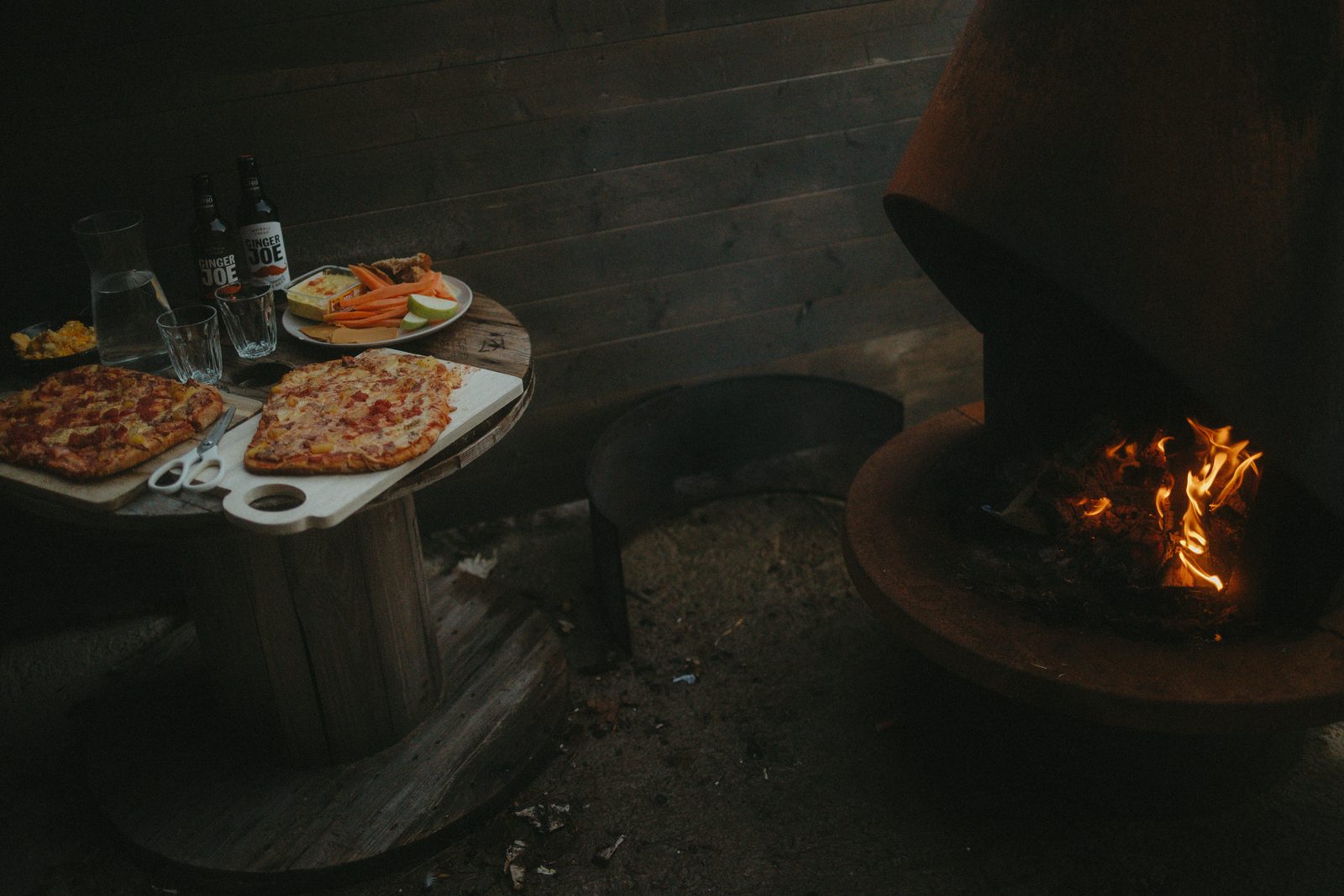 Pizza by the fire pit outside the house.