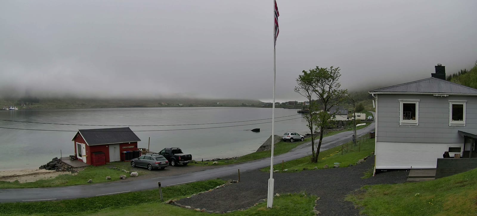 The same view under low grey cloud on the mountains, the road wet, 23 May.