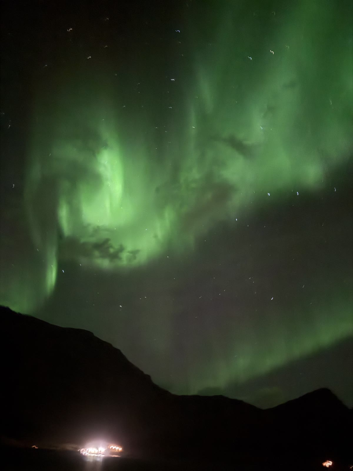 A swirl of green northern lights over the fjord.