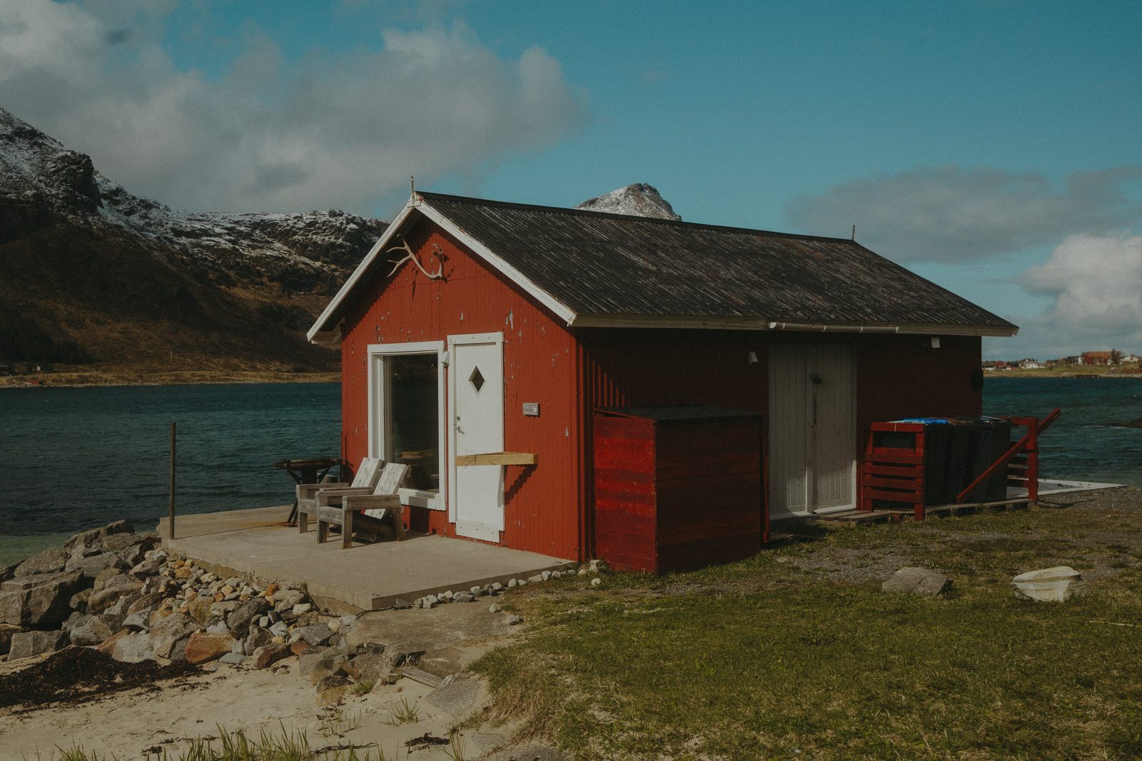 The red boathouse sauna at the water's edge in summer.